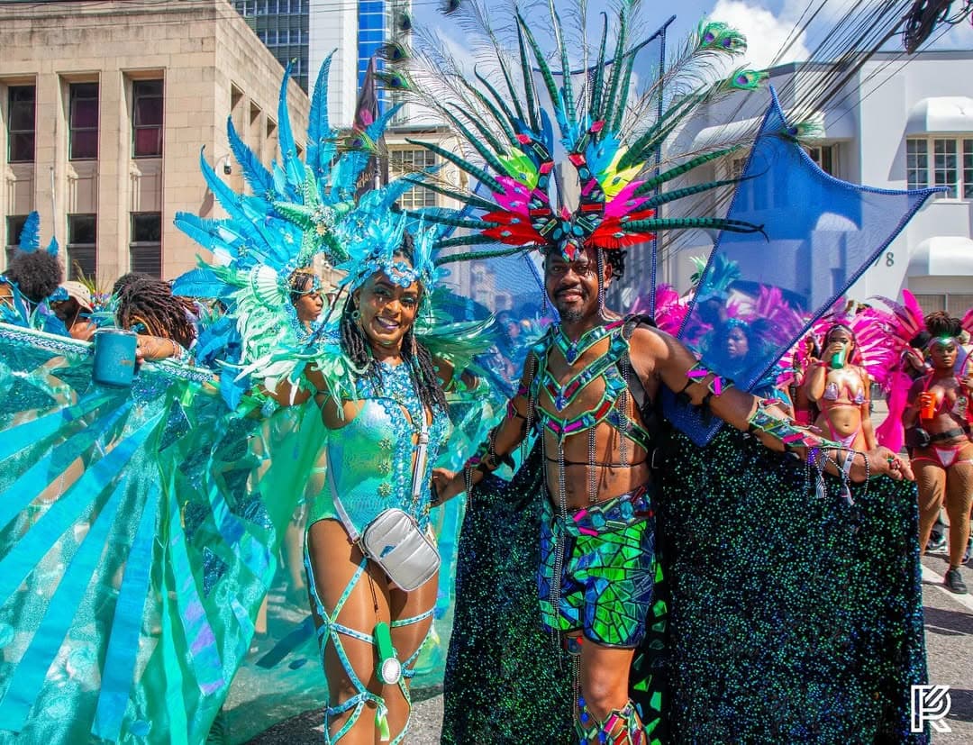 Exousia Mas masqueraders in turquoise feathered costumes on the road during the band's Oceania presentation (2025)
