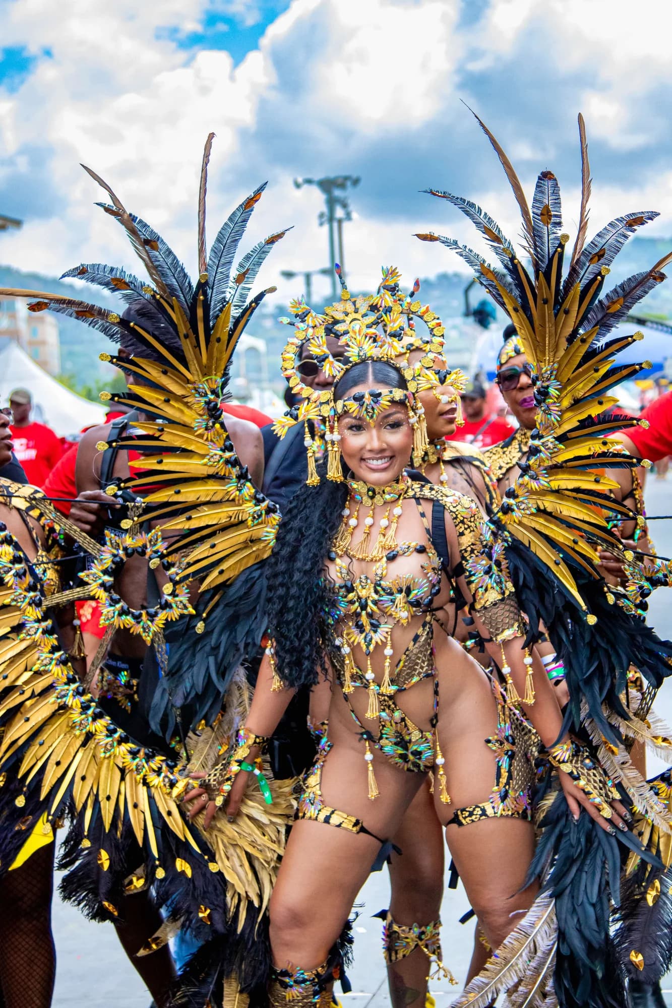 RC Mas masquerader on the road in a black and gold feathered costume and jewelled headpiece