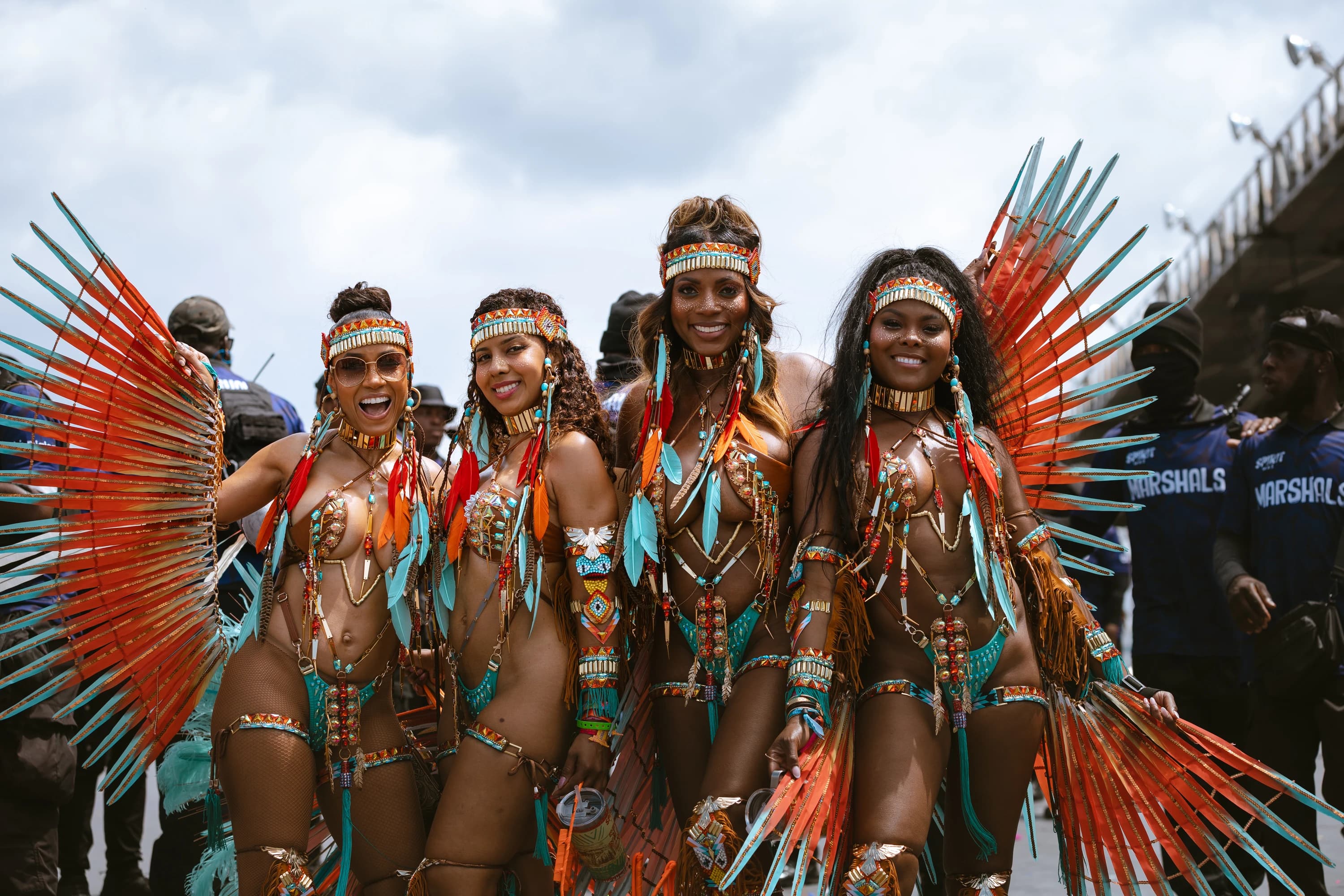 SPIRIT Mas masqueraders on the road in matching orange and turquoise feathered costumes