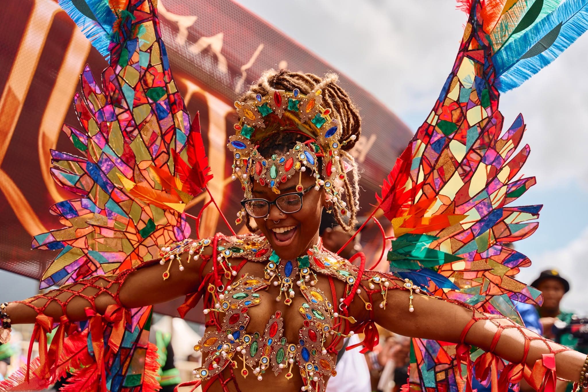 YUMA masquerader on the road in a jewelled costume with orange and red stained-glass style wings